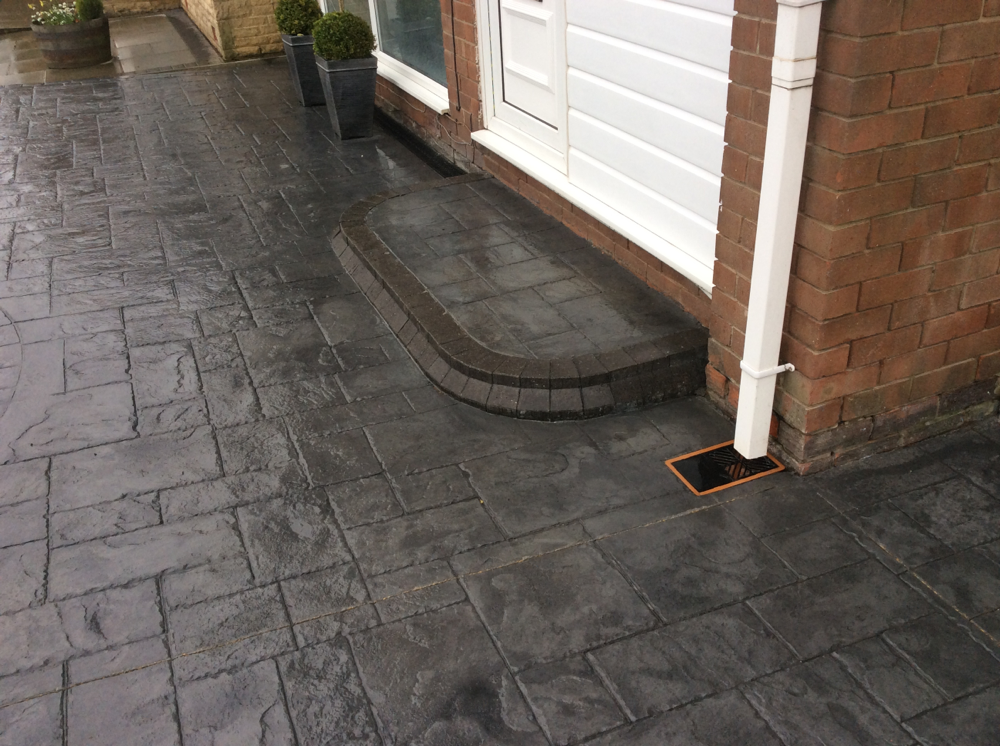 Patterned imprinted concrete driveway installation in Wrexham with curved border